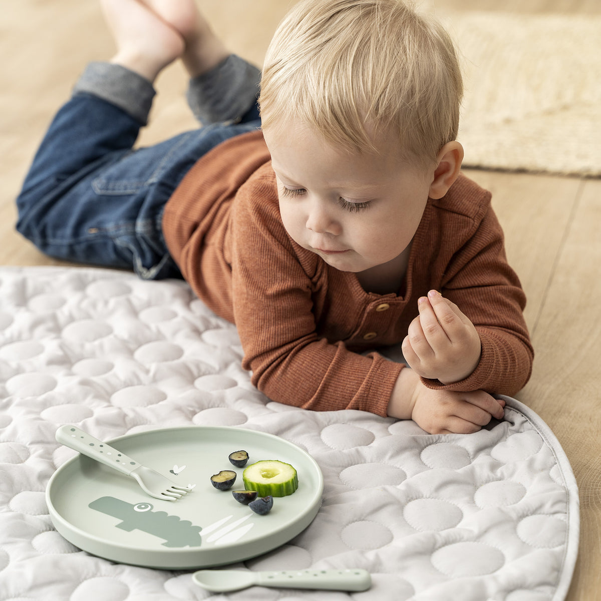 Boy eating from a green foodie plate with Croco the crocoile