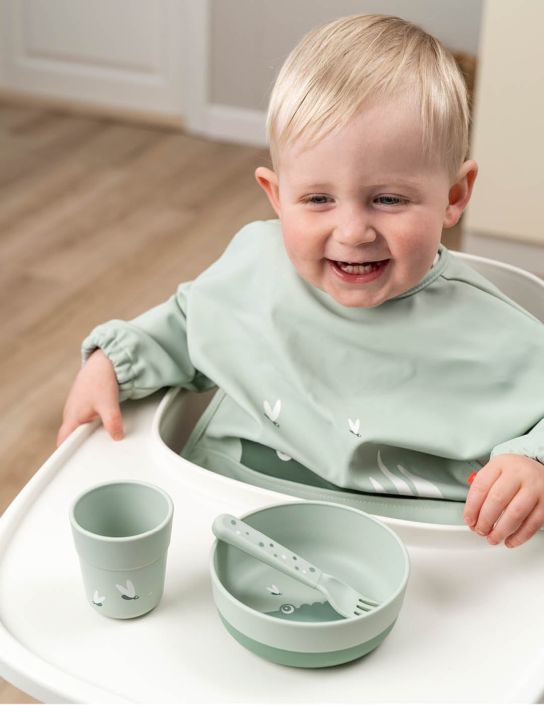 Boy toddler eating from green Done by Deer foodie first meal dinner set with cup, bowl and fork 